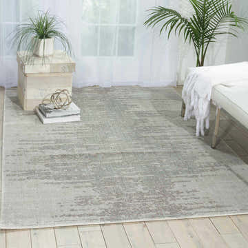 Light and airy room scene with Nourison Twilight Seafoam rug, bench, and plants. Modern style.