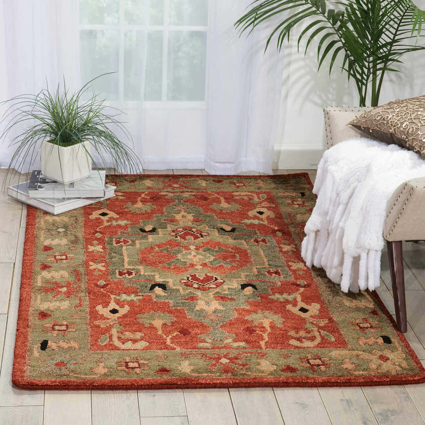 Sunlit room scene with a Nourison Tahoe Rust rug, chair with throw, and plants.