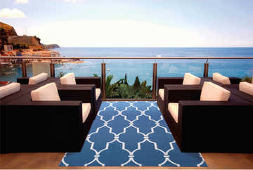 Outdoor patio scene with dark wicker furniture and Nourison Home & Garden Navy Contemporary Area Rug with white geometric pattern.