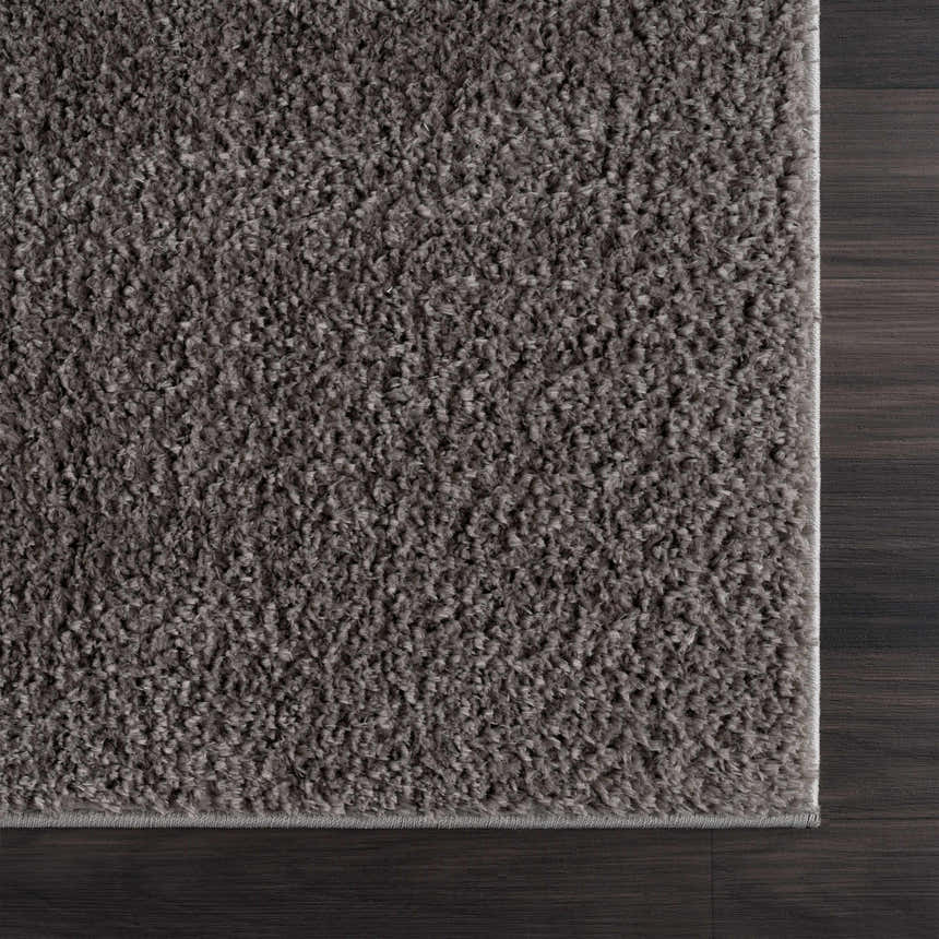 Close-up of the Judy Solid Dark Gray Washable Shag Rug showing its plush texture and color against dark wood flooring. Swatch