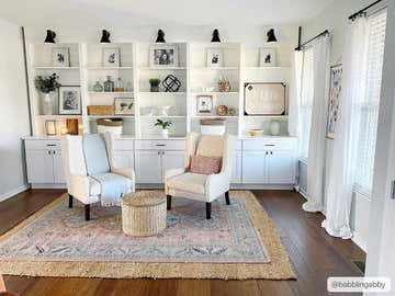 Living room scene with two chairs on a Mantador Area Rug in charcoal, blue, beige, and brown tones. Built-in bookcase. Roomscene-Rectangle