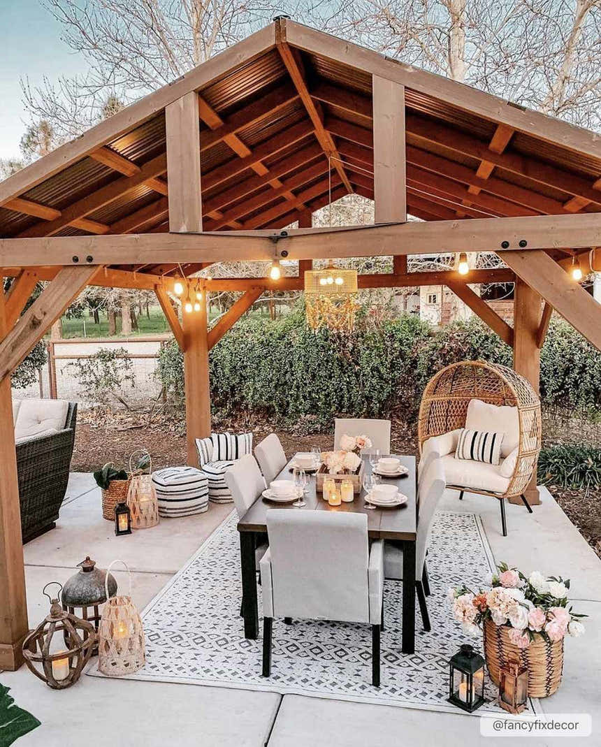 Outdoor dining area with Clenchwarton Textured Beige Rug, wood table, egg chair, lanterns, and string lights. Roomscene-Rectangle