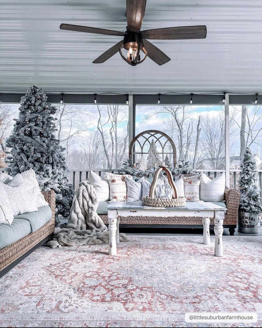 Screened-in porch with a Cream Rust Leeston Washable Rug, wicker furniture, Christmas trees, and a rustic coffee table. Roomscene-Rectangle