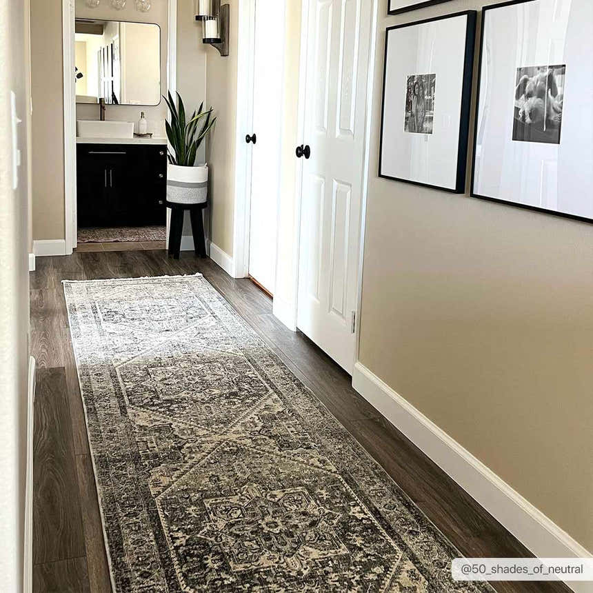 Hallway scene with dark wood floors and the gray Ailsa Area Rug runner. Neutral walls, white doors, and framed art create a cozy feel. Roomscene-Runner