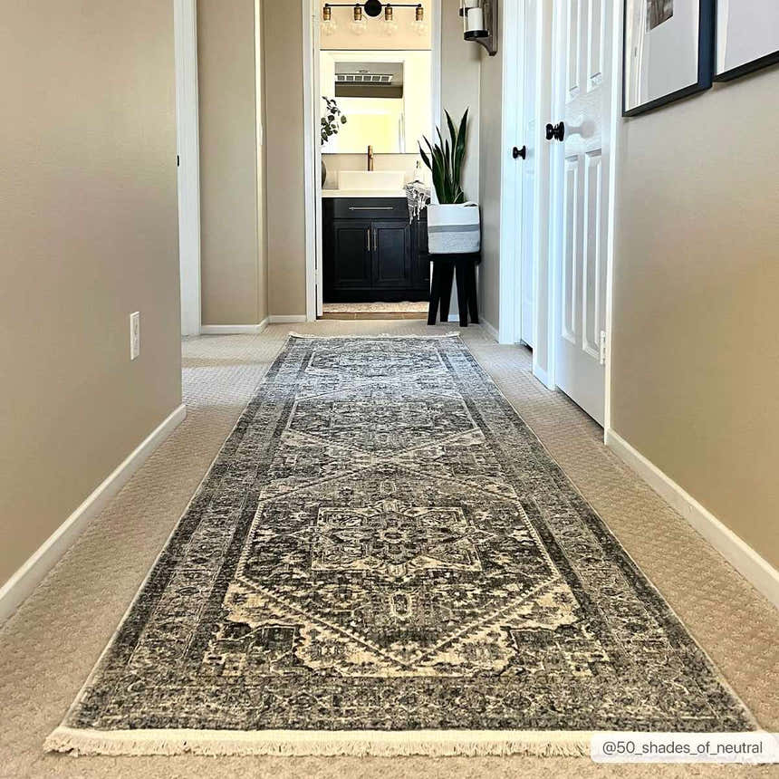 Hallway with a gray Ailsa Area Rug runner leading to a bathroom. Neutral walls, white doors, and a plant add style. Roomscene-Runner