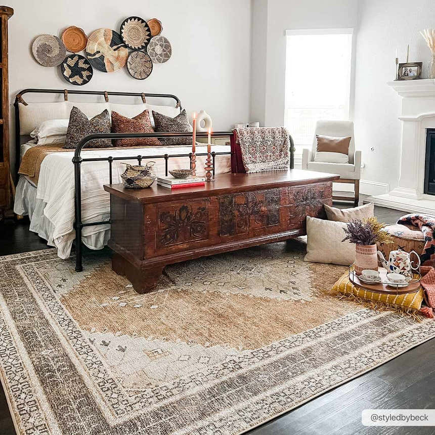 Bedroom scene with a dark brown Albas Washable Area Rug, wood chest, iron bed, and neutral decor for a traditional vintage style. Roomscene-Rectangle