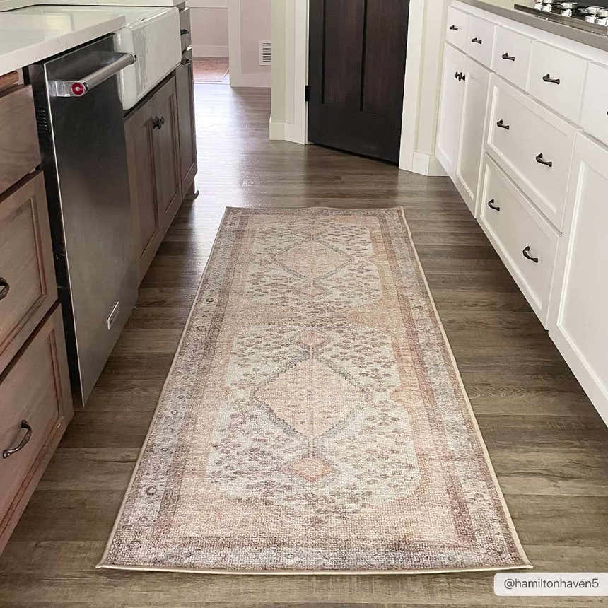 Kitchen scene with a tan Analu Non-Slip Washable Rug runner between wood and white cabinets on dark wood-look floors. Roomscene-Runner