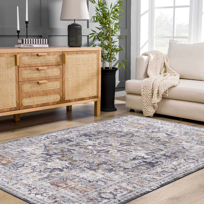 Living room scene with a light wood cabinet and the Ivria Navy & Rust Area Rug on a wood floor. Neutral sofa and gray walls. Roomscene-Rectangle