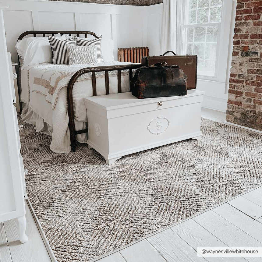 Farmhouse bedroom with white painted floors and Broox Beige Area Rug, iron bed, and white chest. Roomscene-Rectangle