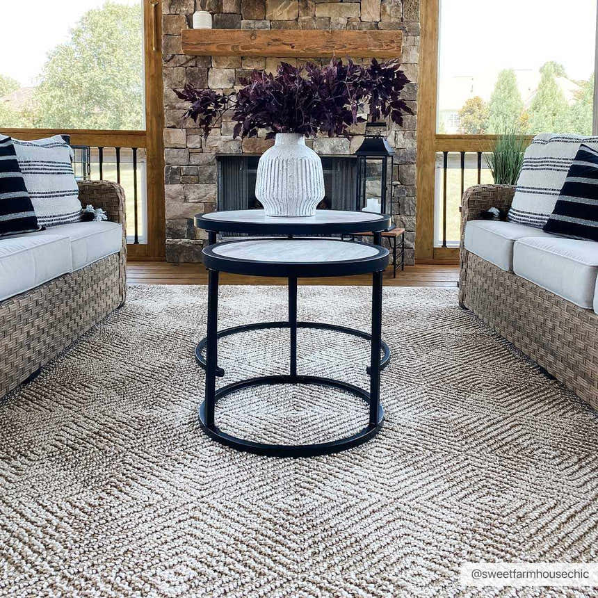 Cozy porch with wicker sofas and Broox Beige Area Rug. Farmhouse style with stone fireplace and round nesting tables. Roomscene-Rectangle