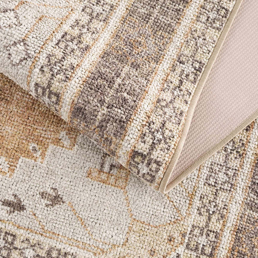 Close-up of the Albas Washable Area Rug. Features a traditional vintage pattern in dark brown, light brown, and light blue hues. Fold