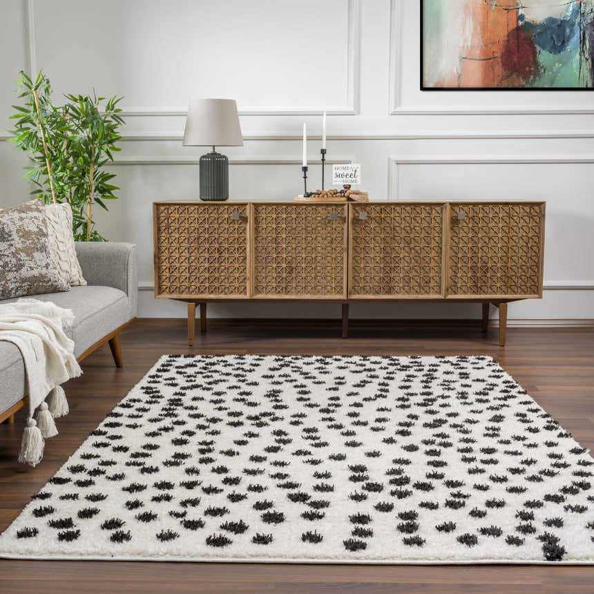 Living room scene with a Cansu Black & White Dotted Area Rug, gray sofa, and wood cabinet. Contemporary style. Roomscene-Rectangle