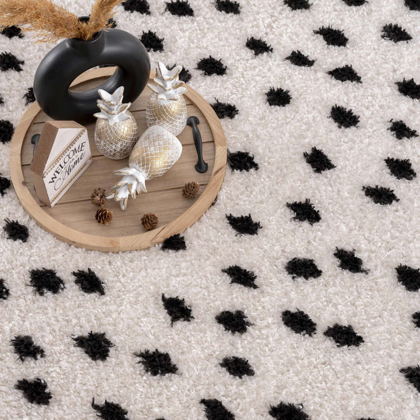 Close-up of the Cansu Black & White Dotted Area Rug, a shag rug with a playful black dot pattern on an off-white, textured base. Styleshot