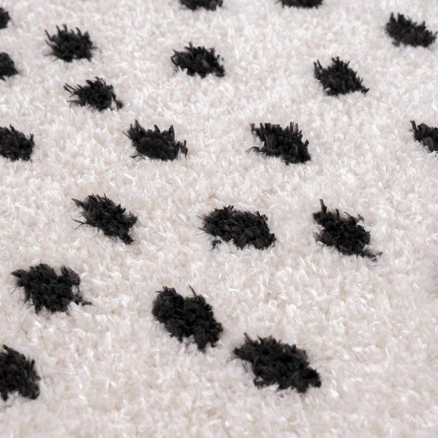 Close-up of the Cansu Black & White Dotted Area Rug. Shag texture with raised black dots on an off-white background. Texture