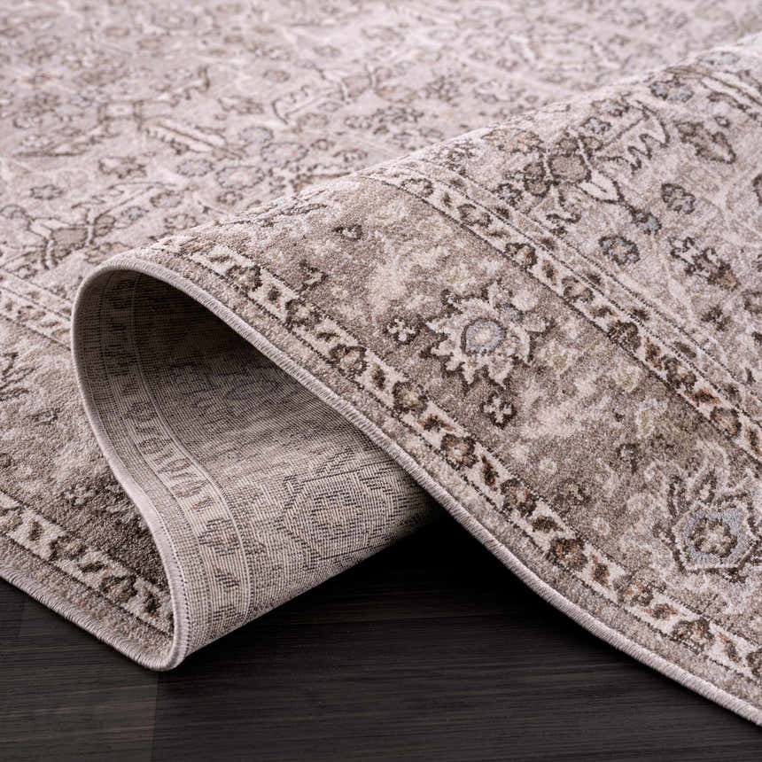 Close-up of a Lugo Luxe Area Rug. Oriental pattern in charcoal, ivory, and light gray. Machine woven polyester rug. Fold