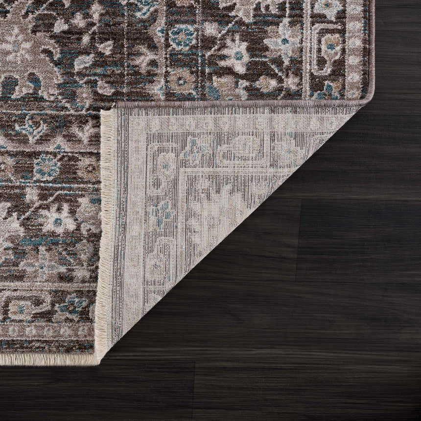 Close-up of the Linmansangan Area Rug showing its dark brown, dusty pink, and pale blue traditional pattern and machine-woven construction. Fold
