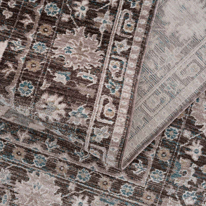 Close-up of the Linmansangan Area Rug. Features a traditional, floral pattern in dark brown, ivory, and pale blue. Fold