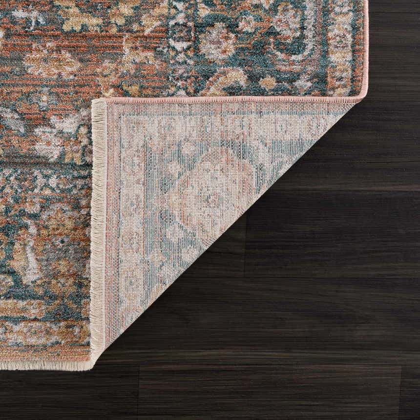 Close-up of the Mele Area Rug showing its traditional design, bone fringe, and colors: burnt orange, olive, and gray. Fold