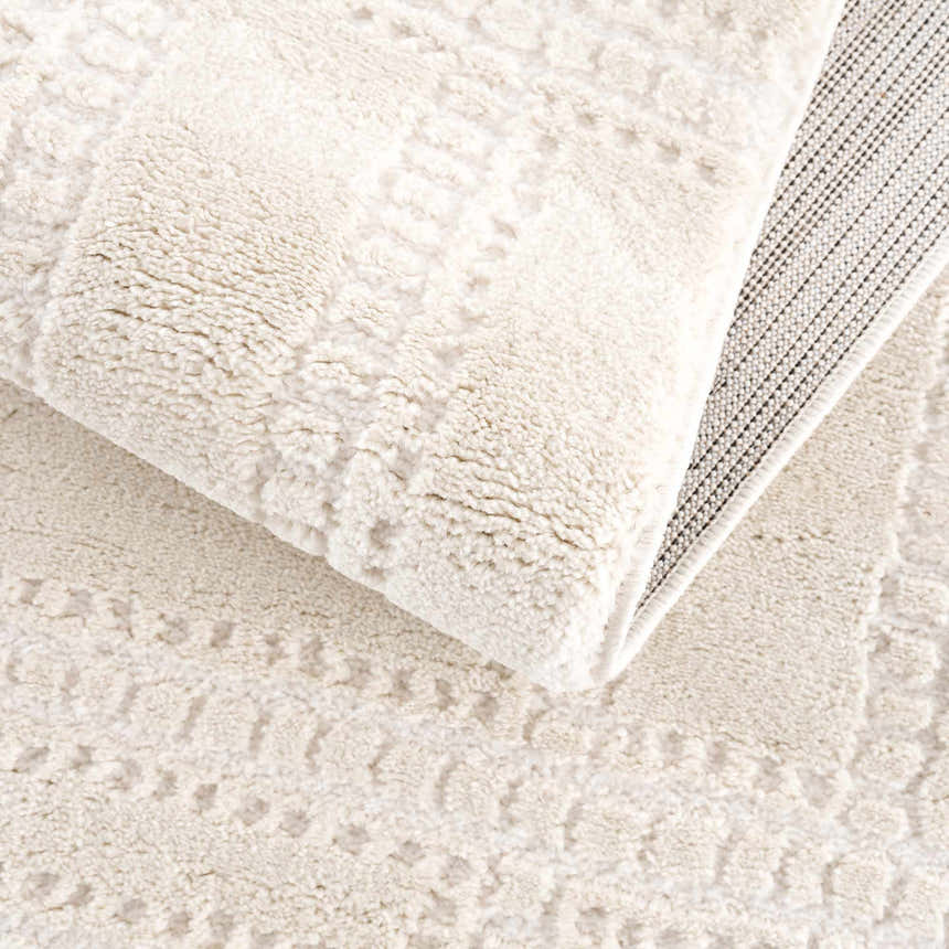 Close-up of the Ryuu Ivory Carved Area Rug showing its plush texture, carved pattern, and neutral beige and cream tones. Fold