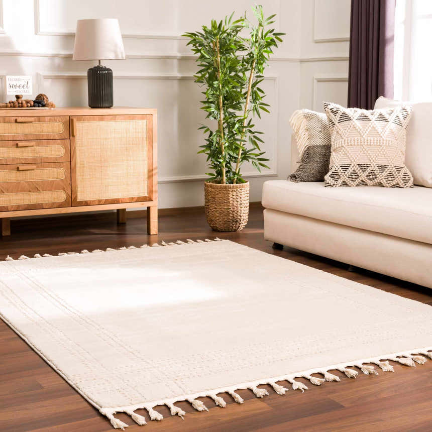 Living room scene with a Ryuu Ivory Carved Area Rug, sofa, wooden cabinet, and plant. Beige and cream tones create a calm mood. Roomscene-Rectangle