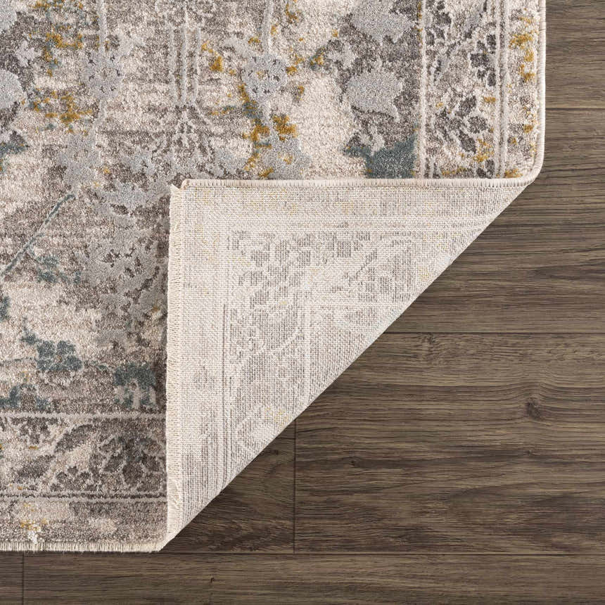 Close-up of the Alroy Textured Rug with Fringes showing its gray, brown, and gold floral pattern and textured weave. Fold