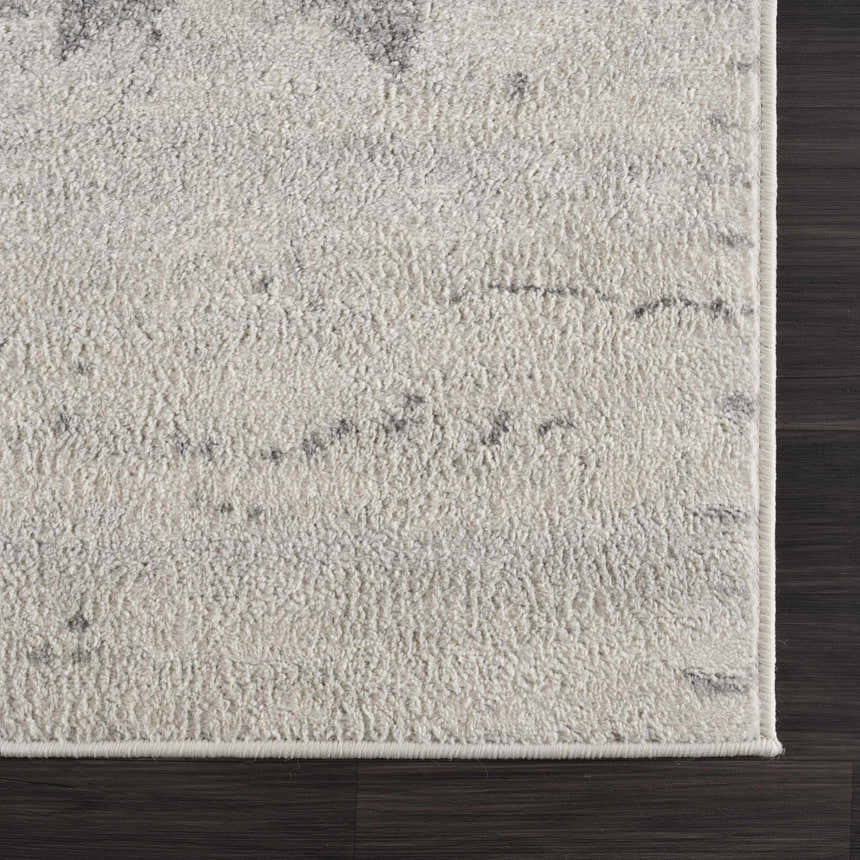 Close-up of the Tigria Ivory 2316 area rug showing its soft texture and subtle gray pattern on a dark wood floor. Corner