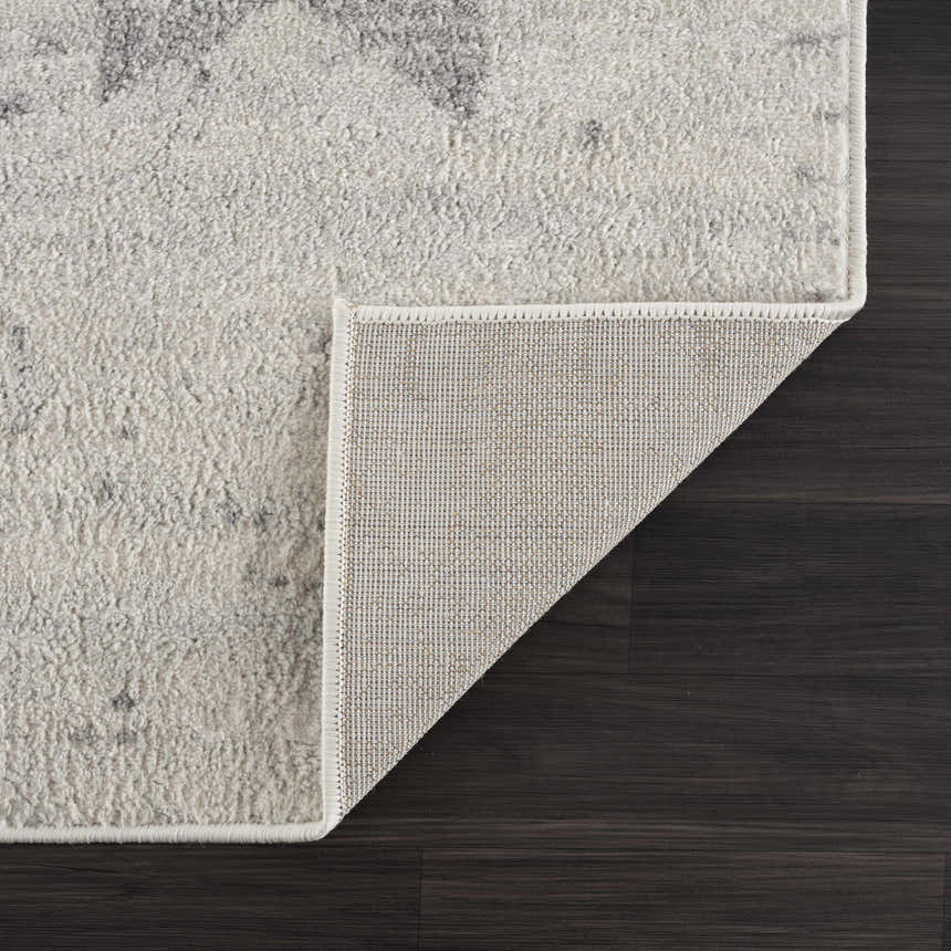 Close-up of the Tigria Ivory 2316 area rug showing its gray and ivory abstract pattern and woven backing. Fold