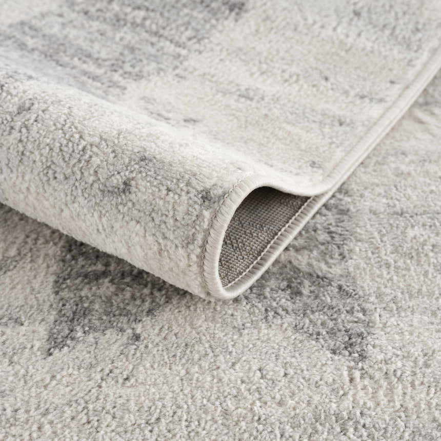 Close-up of the Tigria Ivory 2316 area rug showing its soft texture, gray pattern, and bound edge. Fold