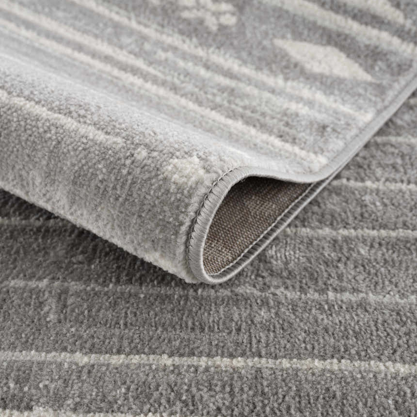 Close-up of the Tigri Aztec Ivory & Gray area rug showing the texture, pattern, and edge binding. Fold