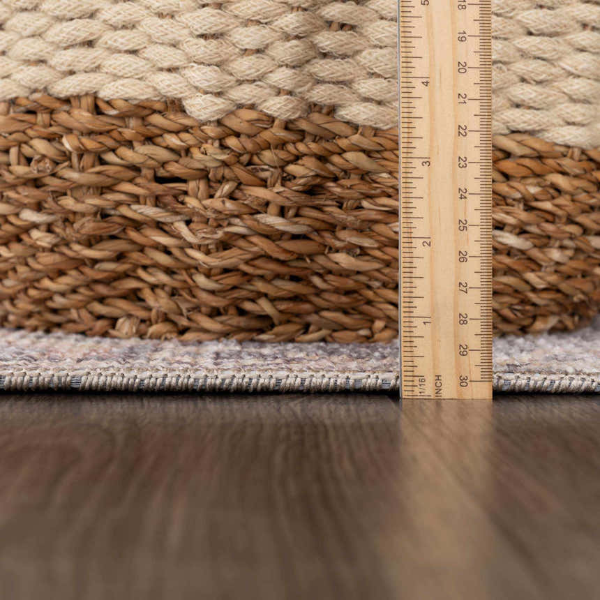 Close-up of the Nyota Area Rug showing its texture and pile height next to a ruler and woven basket. Pile