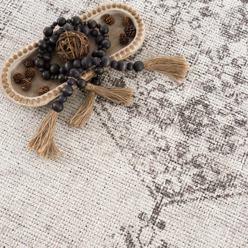 Close-up of Mortye Cream & Brown Medallion rug showing texture and vintage pattern. Styled with wood beads and pinecones. Styleshot
