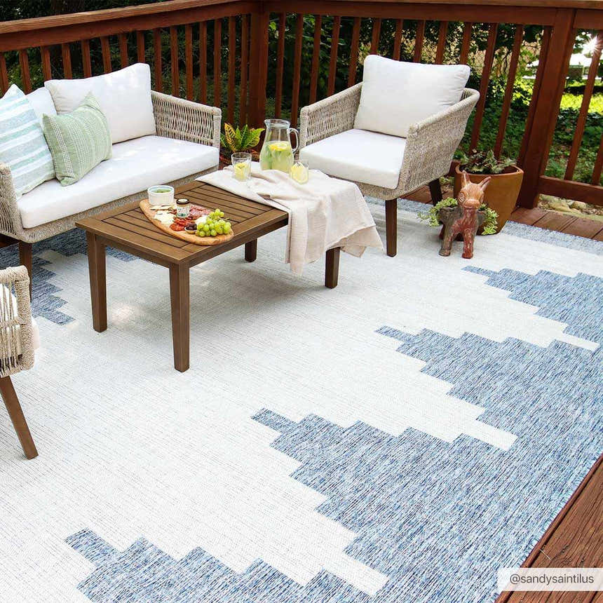 Outdoor deck scene with a Djugun Blue rug, wicker furniture, wood table, and casual entertaining setup. Roomscene-Rectangle