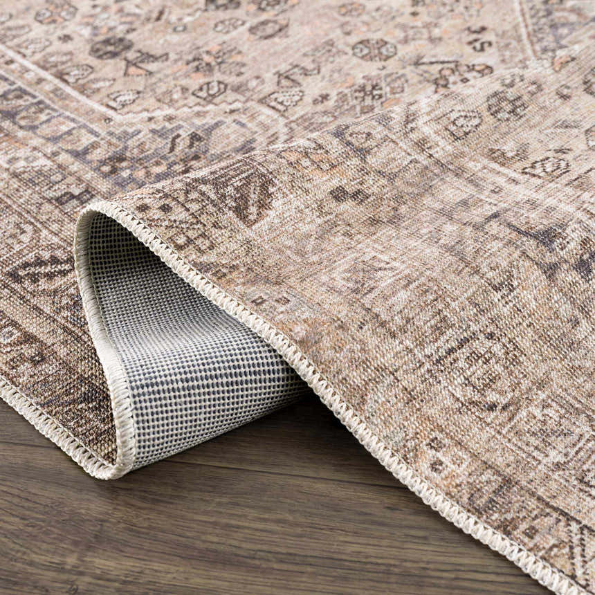 Close-up of the beige Nadie Medallion Area Rug showing its traditional pattern, texture, and non-slip backing. Fold