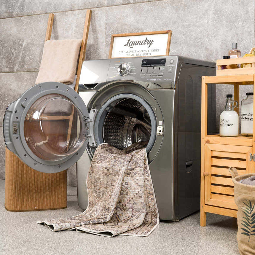 Laundry room scene with a Nadie Beige Medallion Area Rug partially inside a washing machine. Farmhouse style. Washing-Machine