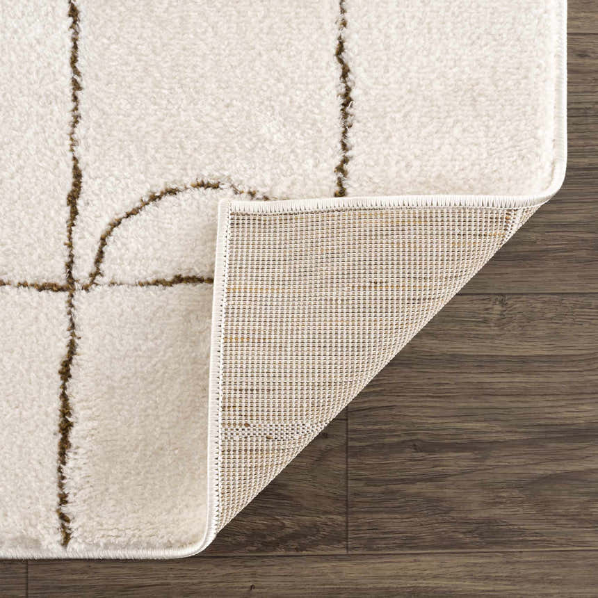 Close-up of the Keanu Area Rug showing its off-white plush texture, brown geometric pattern, and the rug's backing. Fold