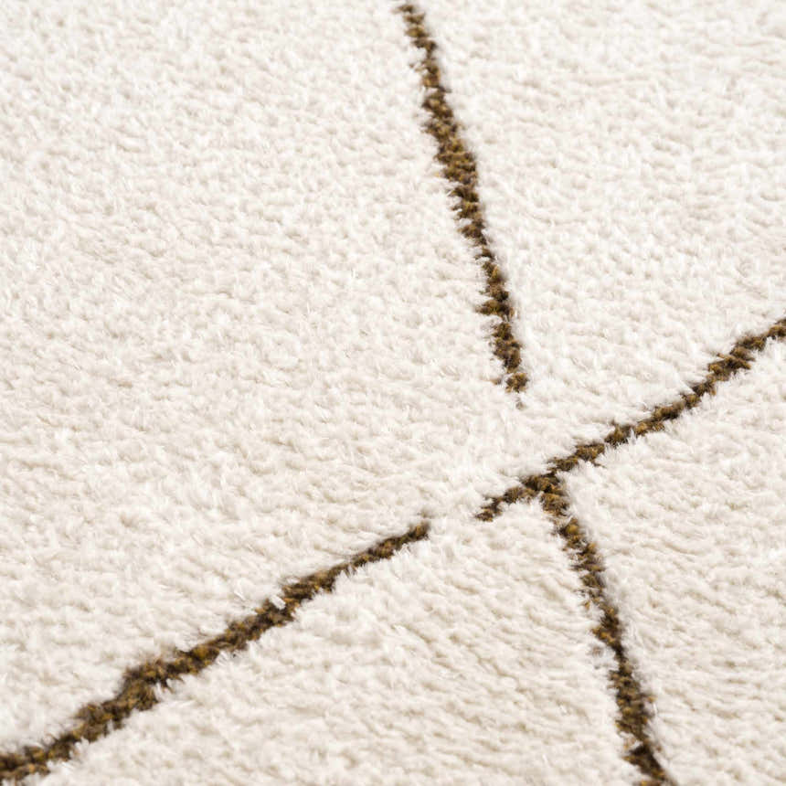 Close-up of Keone Area Rug showing ivory shag texture with brown geometric line pattern. Texture