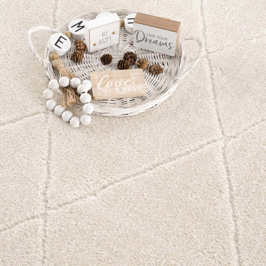 Close-up of the ivory Keone area rug showing the subtle geometric pattern and soft, textured weave. Farmhouse decor accents. Styleshot
