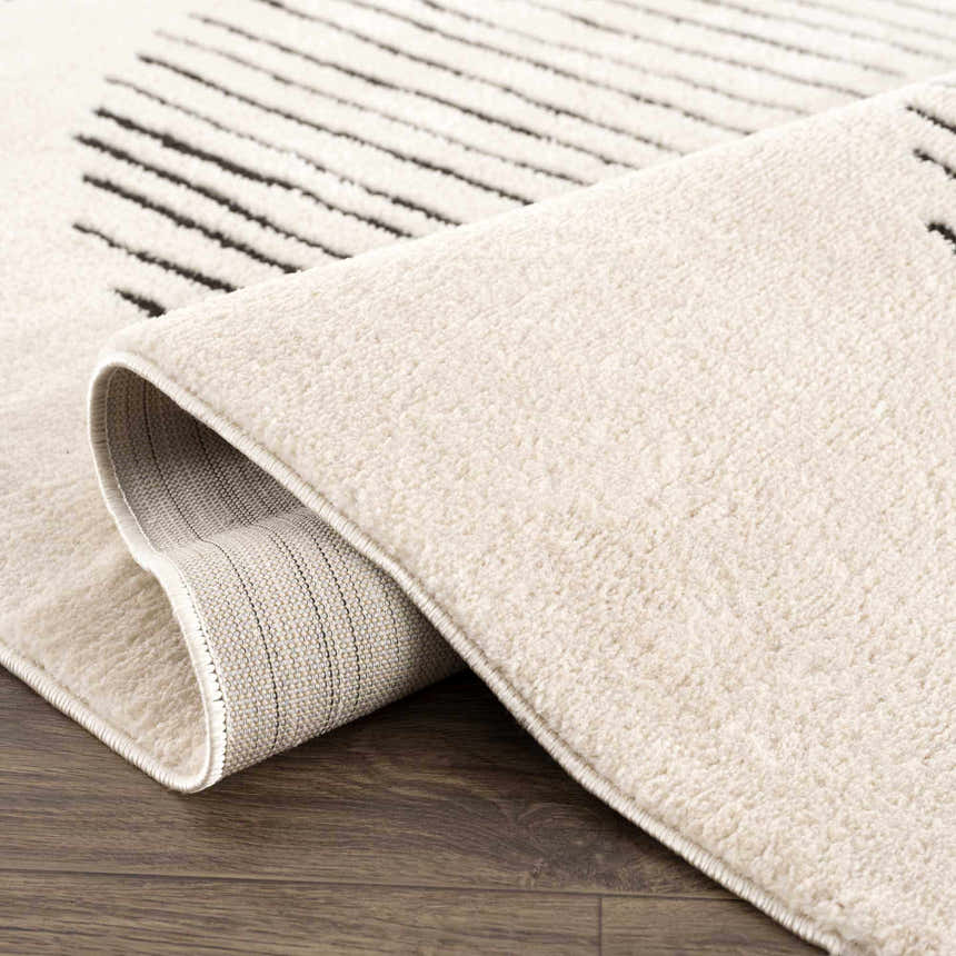 Close up of the cream Mahsa Area Rug with black geometric lines and a soft, plush texture. Fold
