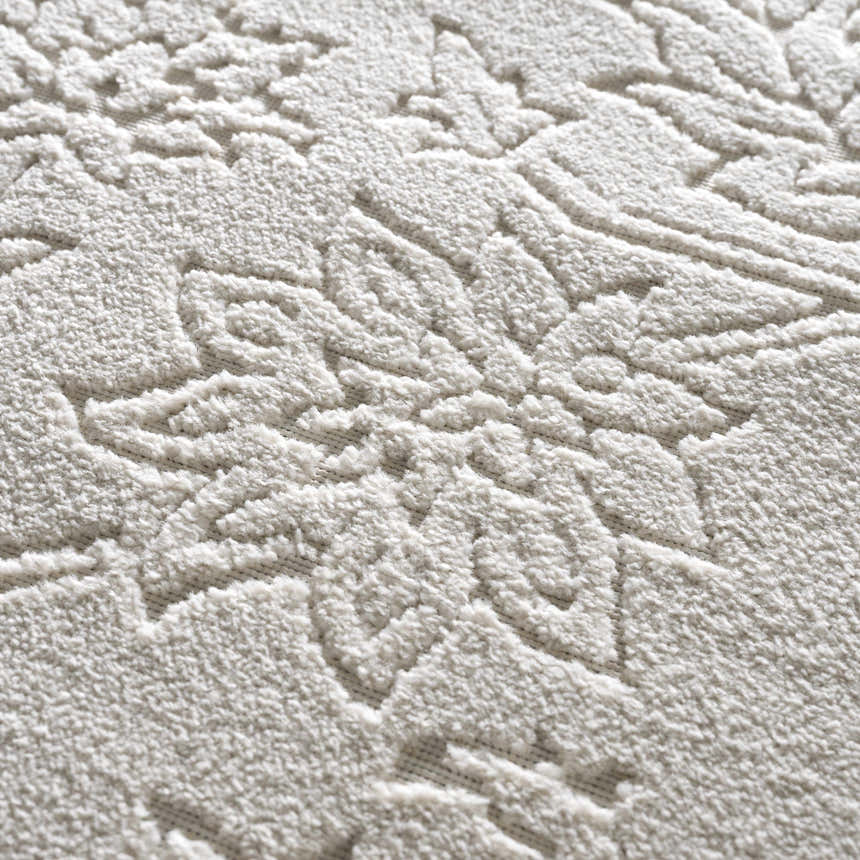 Close-up of the Senekal 3D Outdoor Area Rug. Off-white rug with a raised floral pattern and soft, textured pile. Texture