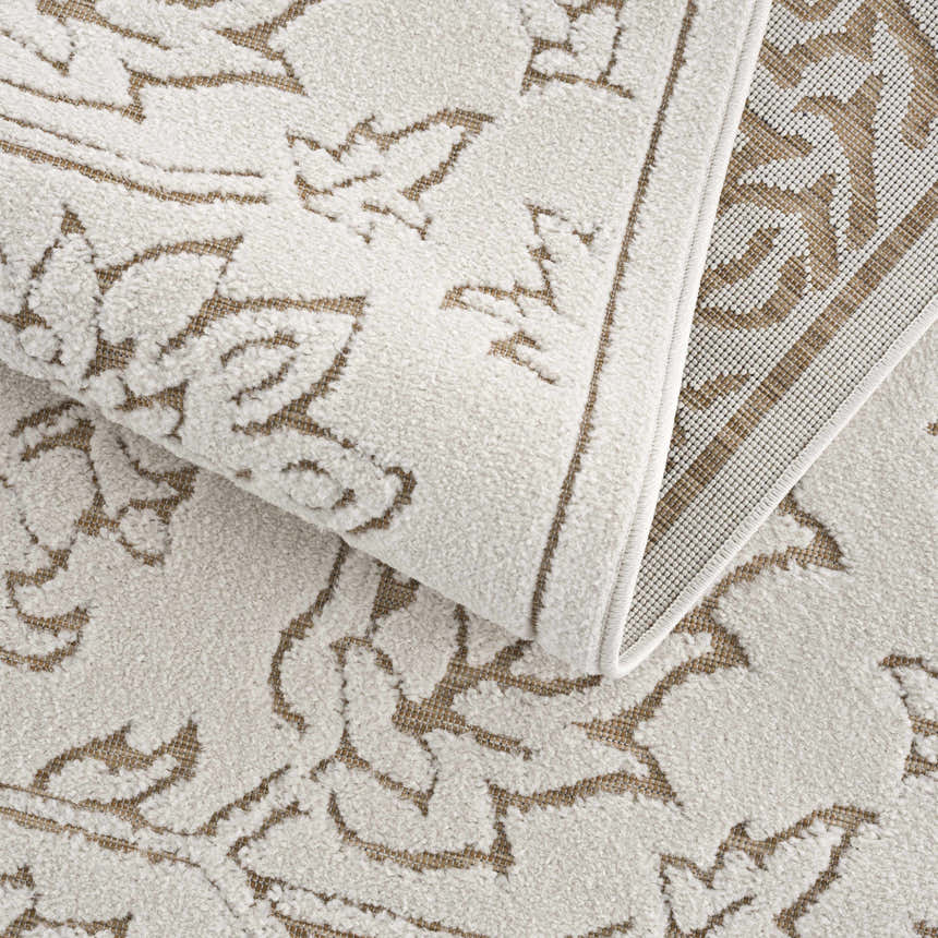 Close-up of the Tabuan 3D Outdoor Area Rug. Features a light peach floral pattern on a white thatch background. Rug backing visible. Fold