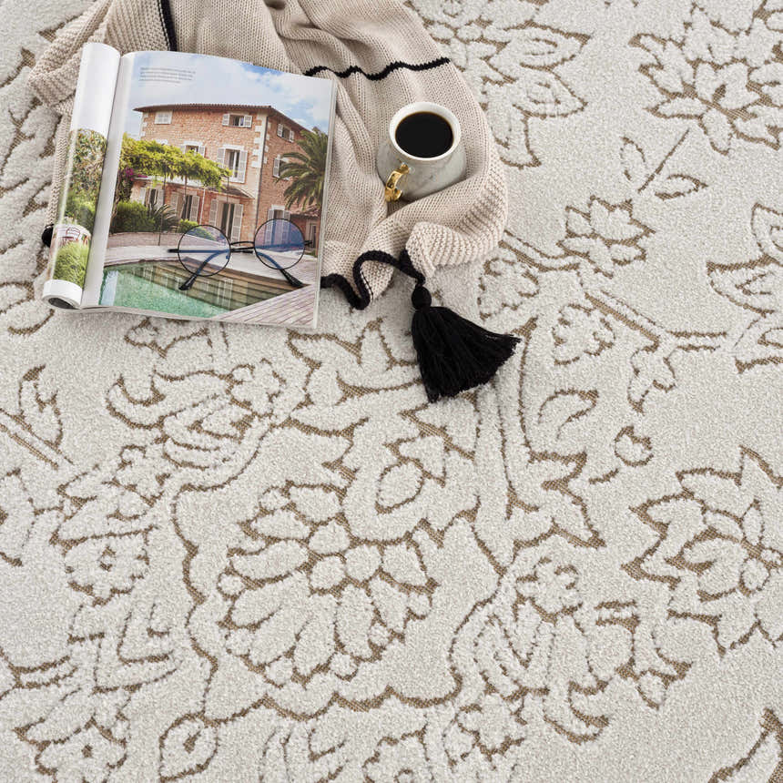 Close-up of Tabuan 3D Outdoor Area Rug. Neutral rug with floral pattern, coffee cup, and magazine. Coastal Grandmother style. Styleshot