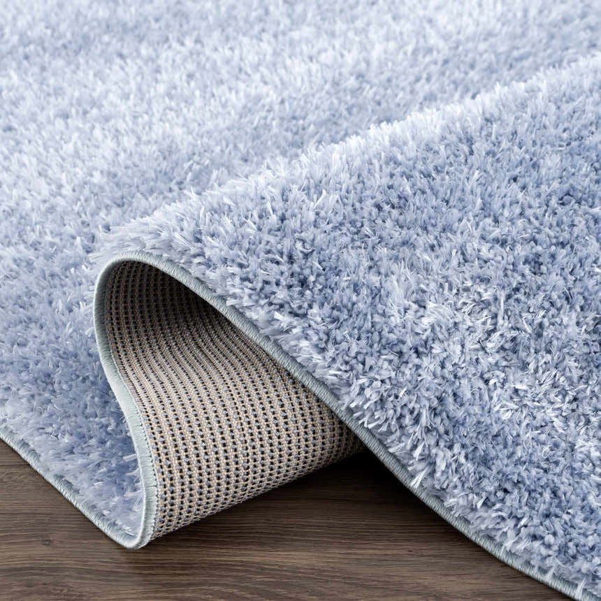 Close-up of the Faina Solid Aqua Shag Washable Area Rug showing its plush texture and backing. Fold