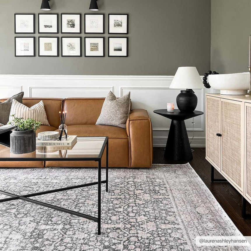 Living room scene with a gray Hedda Boutique Washable Rug, brown leather sofa, and black coffee table. Roomscene-Rectangle