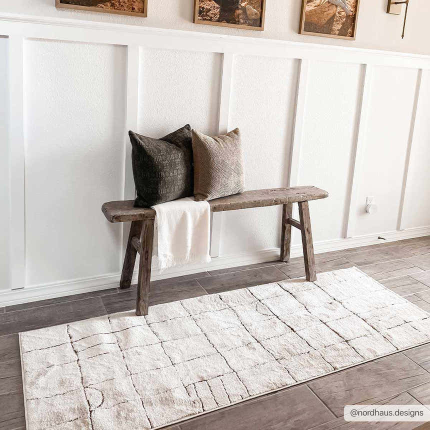 Entryway scene with a geometric beige Keanu Area Rug, wooden bench, and decorative pillows. Roomscene-Runner