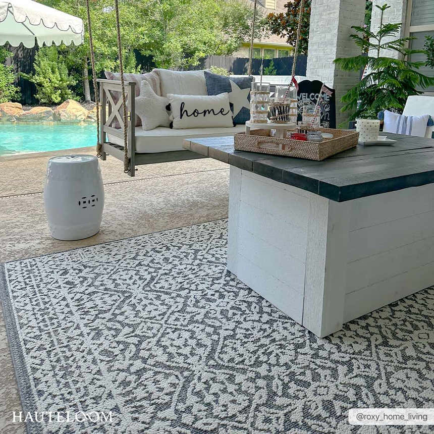 Outdoor patio scene with a gray and white Kinglake Area Rug, swing, and coffee table near a pool. Roomscene-Rectangle