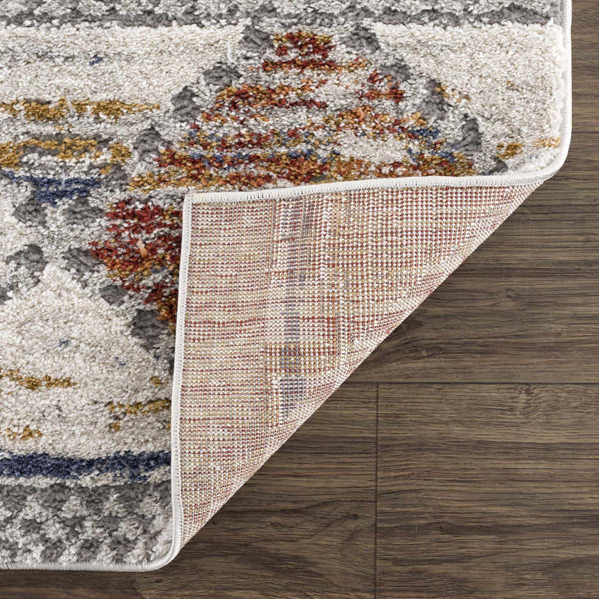 Close-up of the Lelia Area Rug showing its beige, rose cream, blue and grey contemporary pattern and machine woven texture. Fold