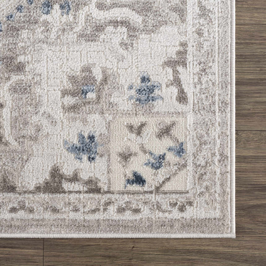 Close up of the Bakir Area Rug, showcasing its blue and gray traditional pattern and soft texture on a wood floor. Swatch