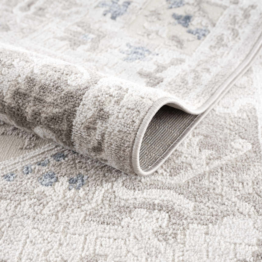 Close-up of the Bakir Area Rug showing its traditional gray and blue pattern and soft, machine-woven texture. Fold