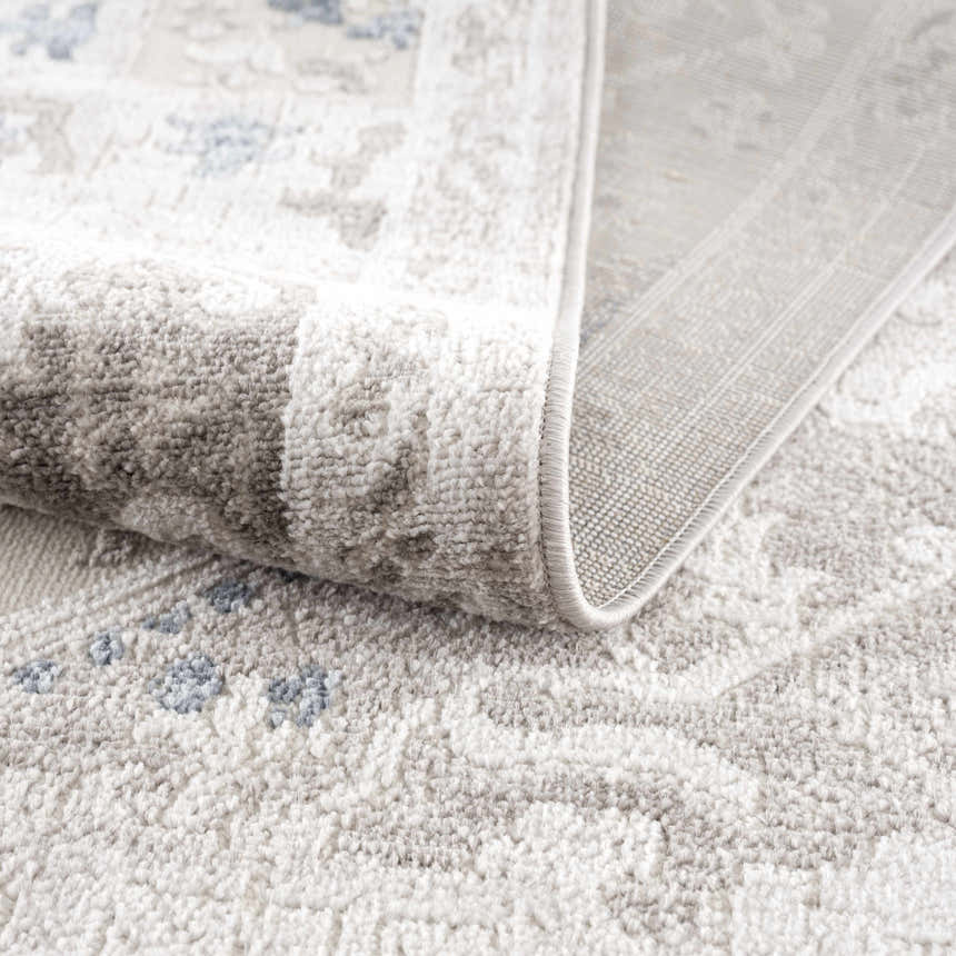 Close-up of the Bakir Area Rug showing its plush texture, gray and blue traditional pattern, and machine-woven construction. Fold