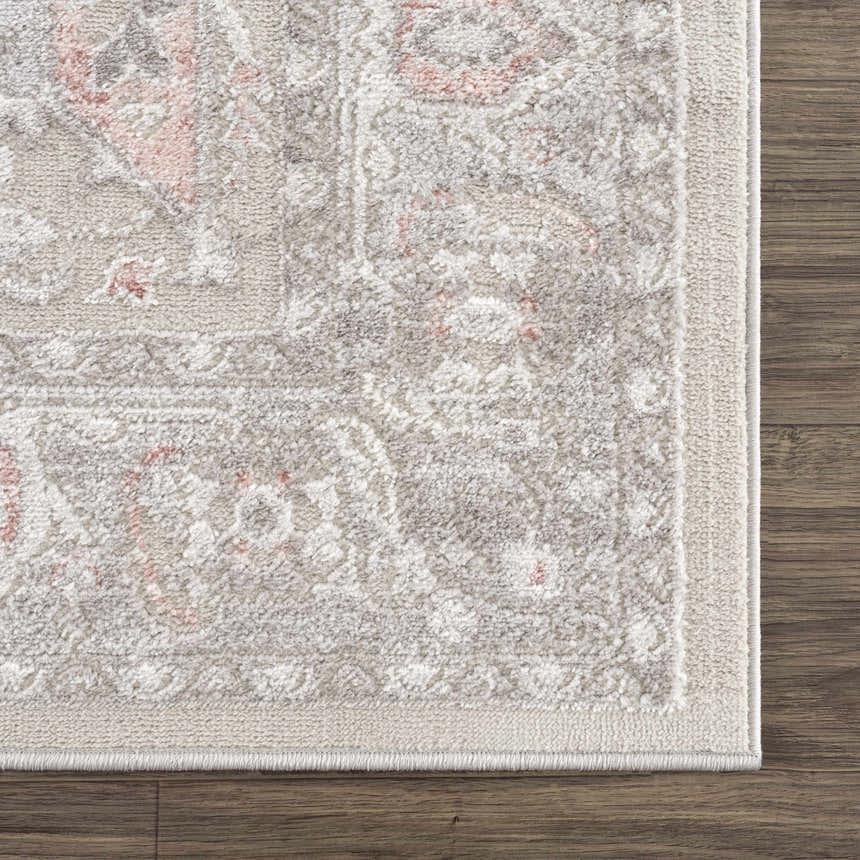 Close-up of the Damla Area Rug showing its gray and pink vintage pattern and soft, textured weave on a wood floor. Swatch
